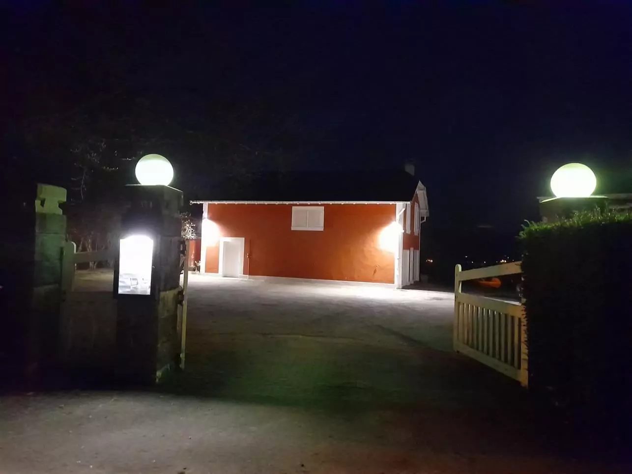 Entrée de propriété éclairée la nuit par des globes sur piliers