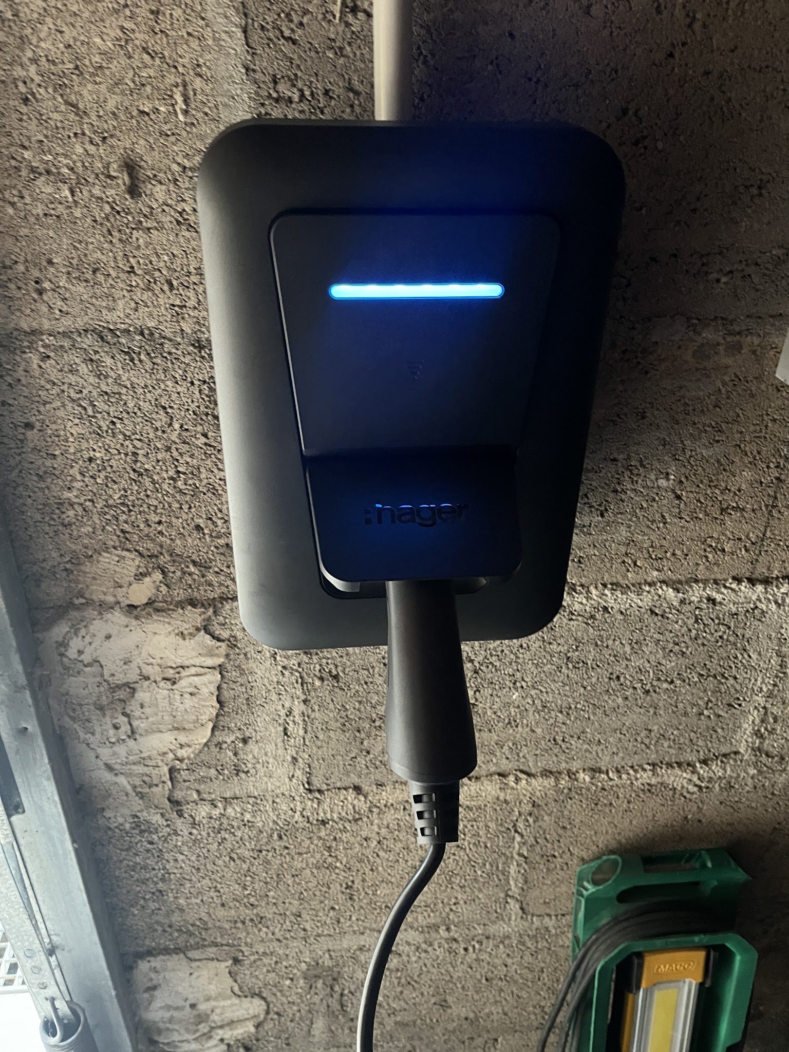 Borne de recharge allumée sur un mur en parpaing